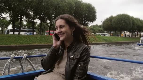 Fiatal nő beszél a telefonon, a folyó túra, városnézés, boldogan mosolygott. A haját szél fúj. Lassú mo — Stock videók