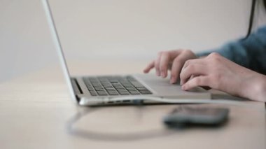 Odada dizüstü bilgisayar üzerinde çalışan bir genç kızın eller