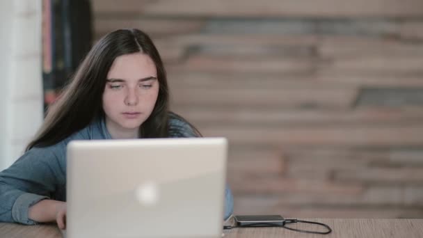 Porträt einer Schülerin, die mit einem Laptop im Internet surft, während sie zu Hause am Tisch sitzt — Stockvideo