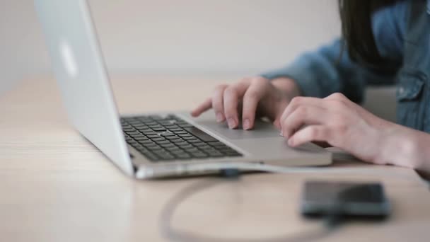 Руки молодої дівчини, що працює на ноутбуці в кімнаті — стокове відео