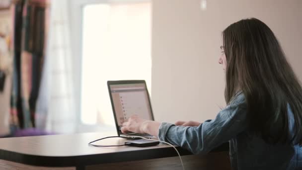 Visão traseira meninas adolescentes usando um laptop sentado à mesa em casa — Vídeo de Stock