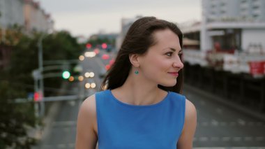 Güzel genç kadın uzun siyah saçlı Rüzgar. mutlu, gülümseyen kız köprüde ayakta ve kameraya benziyor. 4k