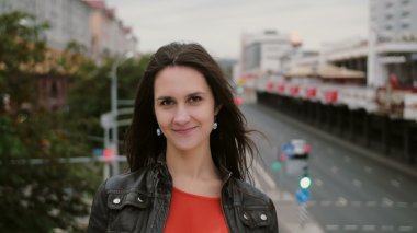 Güzel genç kadın uzun saçlı Rüzgar. mutlu, gülümseyen kız köprüde ayakta ve kameraya 4 k görünüyor