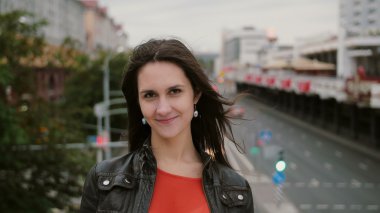 Güzel genç kadın uzun saçlı Rüzgar. mutlu, gülümseyen kız köprüde ayakta ve kameraya 4 k görünüyor
