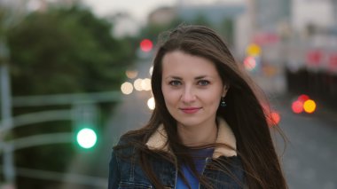 Güzel genç kadın uzun saçlı Rüzgar. gülümseyen kız akşam ve kamera bakar köprüde ayakta. 4k