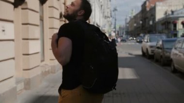 Bir şehri keşfetmek bir sakallı yakışıklı adam siyah sırt çantası, etrafa giyiyor. Güneş parlıyor, yavaş mo, steadicam atış
