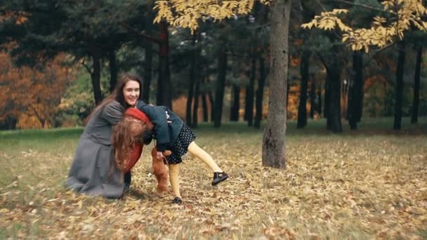 Милая забавная маленькая девочка веселится с мамой в удивительном осеннем парке замедленного действия — стоковое видео