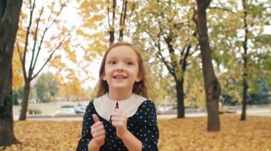 kıvırcık saçlı portre sevimli küçük kız, polka noktalı elbise gülmek, atlamak, sonbahar parkı yavaş mo eğlenin