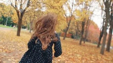 kıvırcık saçlı sevimli küçük kız yakın, park yavaş mo sonbahar sokak boyunca çalışan polka noktaları ile elbise