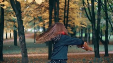 komik, neşeli sevimli küçük kız onu oyuncak ile dönen, oyuncak ayı sarı yaprakları ağaç yavaş hareket onlara düşmek