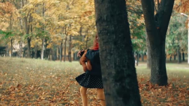 drôle, joyeuse petite fille mignonne filant avec son jouet, ours en peluche jaune dans l'incroyable parc d'automne au ralenti 