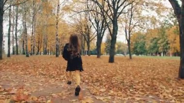 kıvırcık saçlı mutlu sevimli küçük kız parkta yavaş mo sonbahar sokak boyunca çalışan