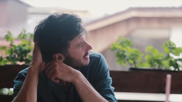 Sleepy tired young attractive man sits at a table outdoors — Stock Video