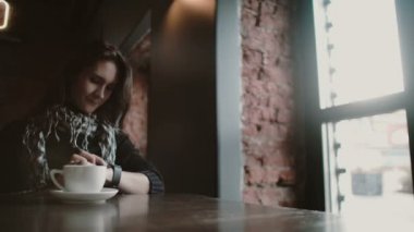 Çatı Cafe 4 k pencere bakarak onun smartwatch dokunmatik ekran cihaz kullanan kadın