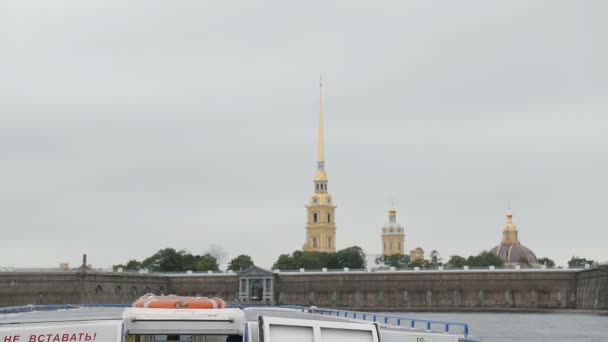 Достопримечательности Санкт-Петербурга. Вид на Петропавловскую крепость из речного автобуса, поворачивающего налево возле набережной, медленное время — стоковое видео