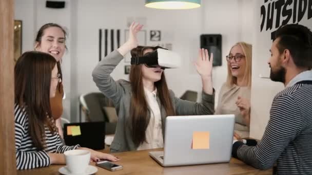 Première expérience avec des lunettes de réalité virtuelle jeune équipe soutient jeune belle fille brune dans le bureau de démarrage moderne — Video