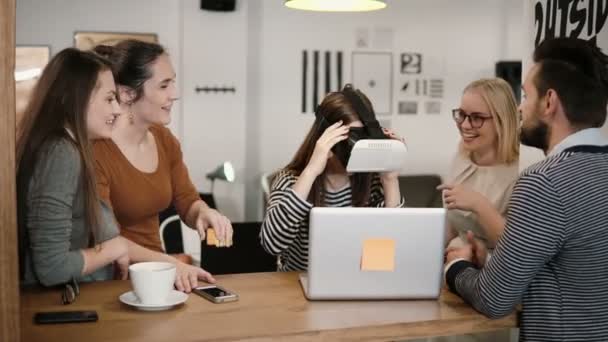 Første erfaring med virtual reality briller unge hold understøtter ung smuk brunette pige i moderne opstart kontor – Stock-video