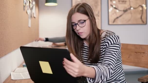 Menina atraente jovem trabalhando com laptop em um escritório de inicialização moderna — Vídeo de Stock