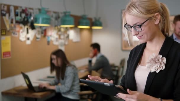 Hermosa mujer de negocios rubia utiliza una tableta en el equipo moderno de la oficina de inicio en el lugar de trabajo lento mo, steadicam shot — Vídeos de Stock