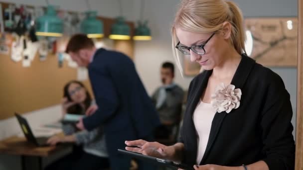 Hermosa mujer de negocios rubia utiliza una tableta en el equipo moderno de la oficina de inicio en el lugar de trabajo lento mo, steadicam shot — Vídeo de stock