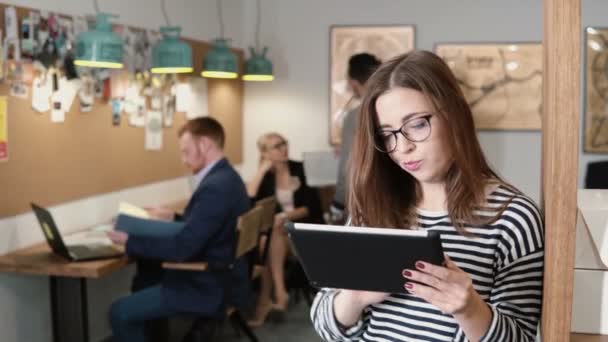 4k. Nahaufnahme junge attraktive brünette Geschäftsfrau nutzt ein Touchscreen-Tablet im modernen Startup-Büro. — Stockvideo