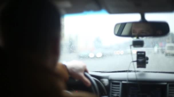 Nahaufnahme lächelnder Männer während der Fahrt bei Regenwetter. Linke Hand am Lenkrad. viel befahrene Straße. Anreise mit dem Auto. — Stockvideo