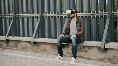 Sakallı çekici adam çatıda sanal gerçeklik gözlük kullanır, gözlüklerini alır ve uzaklaşır. 4k