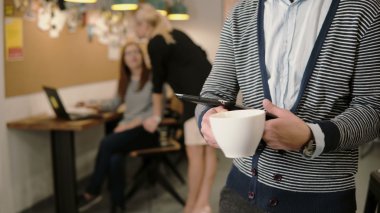 eller genç adam close-up dokunmatik tablet ve içme kahve modern başlangıç ofiste kullanır.