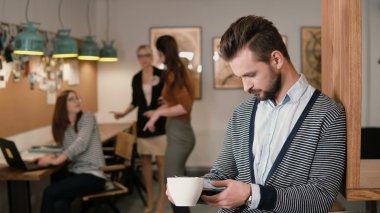 genç yakışıklı sakallı adam dokunmatik tablet ve içme kahve modern başlangıç ofiste kullanır.