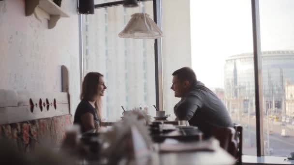 Zijaanzicht van een jonge man en vrouw die kijken naar elkaar, gesprek. Mooi uitzicht op de stad straat uit raam. — Stockvideo
