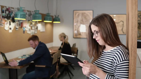 4k. primer plano joven atractiva morena empresaria utiliza una tableta de pantalla táctil en la moderna oficina de inicio . — Foto de Stock