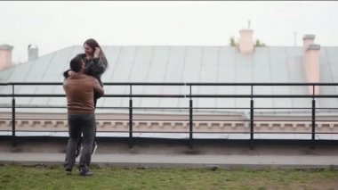 Adam onun sevgili kollarını kaldırdı ve çevresinde bir çatı swirls. Mutlu aşıklar birlikte soğuk havalarda eğlenin