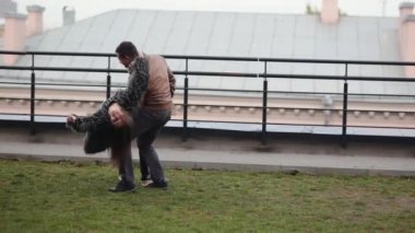 Genç çift ayakta bir çatı gülmek iyi eğlenceler. Esmer aşık güzel bir manzara. Mutlu aşk ilişkisi.