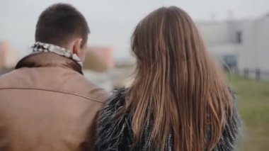 Koyu renk saçlı bir çiftin bir çatı yürüyüşe sahip, öpüşme, konuşmak Backview. Uyum içinde ilişki.