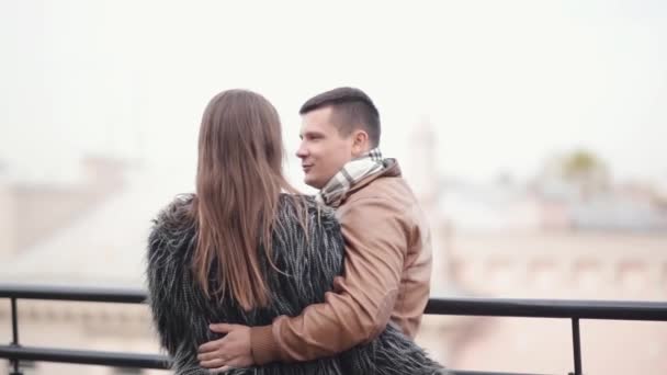 Vista trasera de una pareja en un techo de un edificio en una ciudad. Los amantes de hablar, reír pasar un buen rato juntos, disfrutar de la vista — Vídeos de Stock