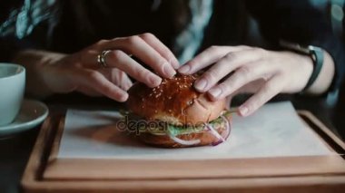 Lezzetli burger bir ahşap tepsi üzerinde çok güzel. Bir kadının elleri alır ve yemek için gidiyordu.