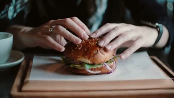 Le burger savoureux est excellent sur un plateau en bois. Une femme prend ses mains et allait manger . — Video