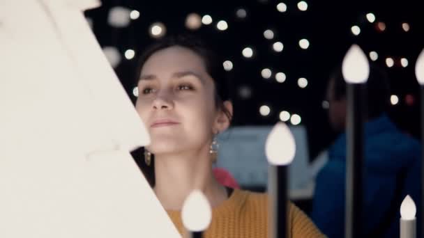 Young attractive brunette girl at the store chooses lamps, Christmas decor. — Stock Video