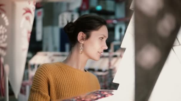 Joven chica morena atractiva en la tienda elige lámparas, decoración de Navidad . — Vídeos de Stock