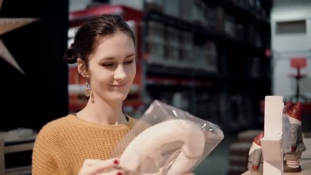 Attrayant jeune femme heureuse choisit en magasin couronne de Noël. décor pour intérieur de la maison — Video