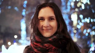 parlak ışıklar, kamera önünde park ağaçlar bakarak karlı Noel gecesi smiles çekici kadın dekore