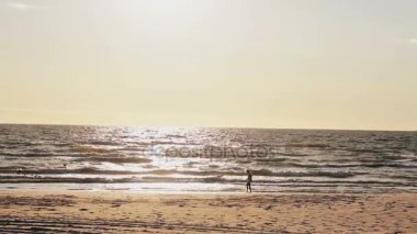 Beyaz elbiseli genç kız doğru ayağa gelen dalgalar ile güneş yaktı kumlu bir plaj üzerinde yürüyor