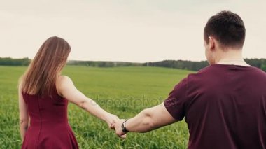 Romantik genç çift elele, uzun otların bir alana yürürken seviyorum. Yavaş mo, steadicam vurdu