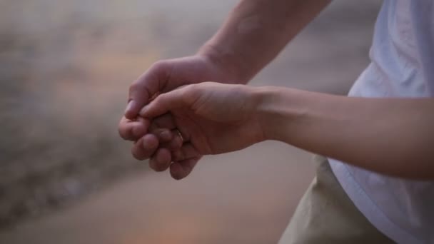 Крупным планом руки молодой пары мягко похлопывают друг друга по пляжу — стоковое видео