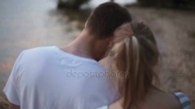 yakın çekim geri görüntüleyin. Genç aşıklar erkek ve kadın gün batımında göl kenarı boyunca yürüyüş