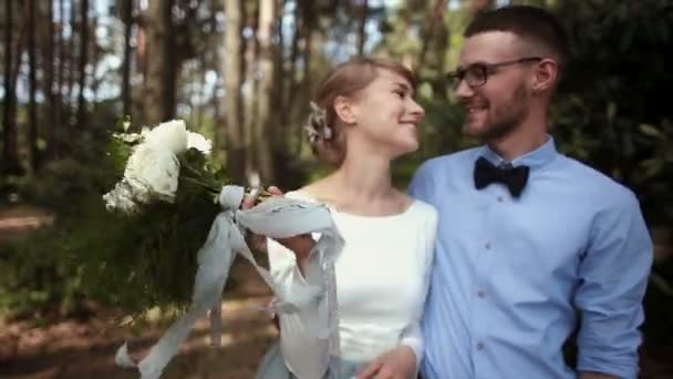 Mladý nádherný pár novomanželů polibek na pozadí zelených stromů v parku — Stock video