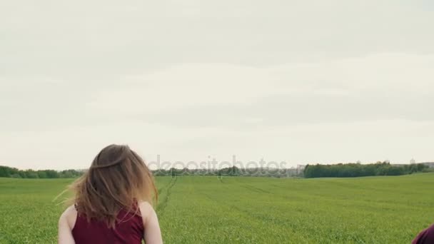 Beautiful woman teases her lover running away in a field, he chases. Happy lovers have fun. Slow mo, steadicam shot — Stock Video