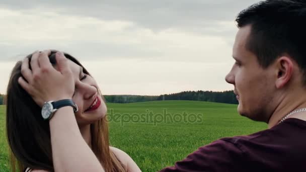 Close-up of a loving couple in the nature. Man kisses his beloved woman and hugs her. Brunette woman is smiling. Slow mo — Stock Video