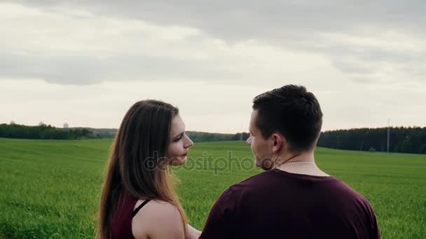 Mooie Achteraanzicht van liefdevolle paar in een veld, kijken naar elkaar. Vrouw leunt op haar hoofd aan schouder mans. Slow mo — Stockvideo