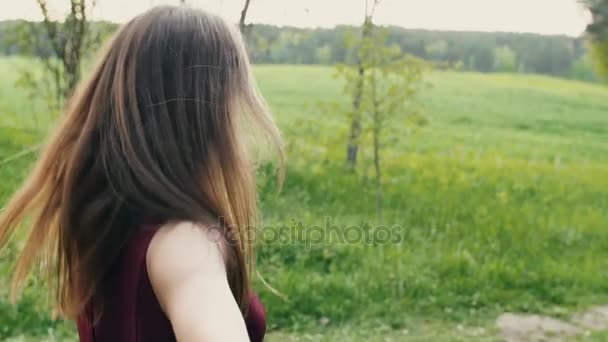 Frau dreht ihr Gesicht, lächelt in die Kamera, während sie in der Natur rennt. dunkles Haar wiegt. slow mo, steadicam shot — Stockvideo